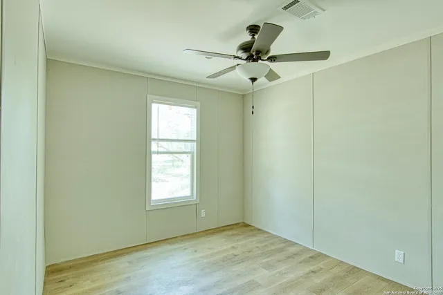 an empty room with a window and a ceiling fan