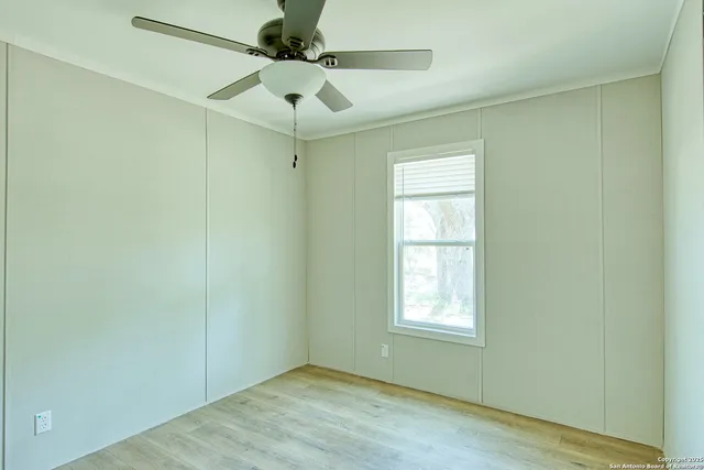 an empty room with a window and a fan