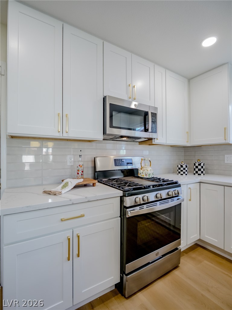 321 Lakehurst Road Las Vegas, NV 89145 - Photo 11 of 33 Quartz countertops and stainless steel appliances define this modern kitchen with white shaker cabinetry.