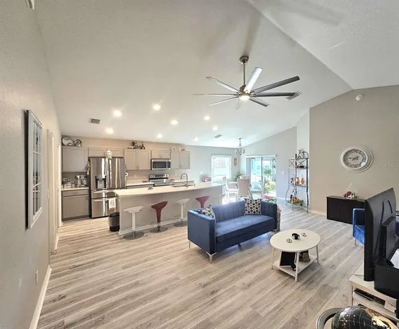 a living room with stainless steel appliances furniture and a kitchen view