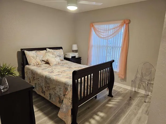 a bedroom with a bed and dresser with wooden floor