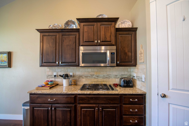 646 East 1400th Street North Mapleton, UT 84664 - Photo 21 of 78 Kitchen featuring dark wood cabinetry, a stainless steel built-in microwave, a gas cooktop, stone countertops, and a tiled backsplash