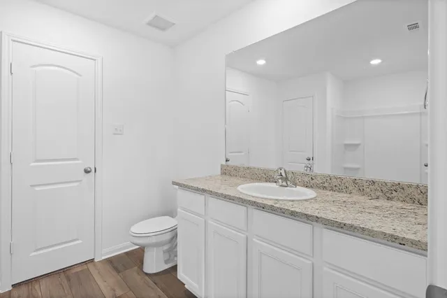 a bathroom with a granite countertop sink a toilet and a mirror