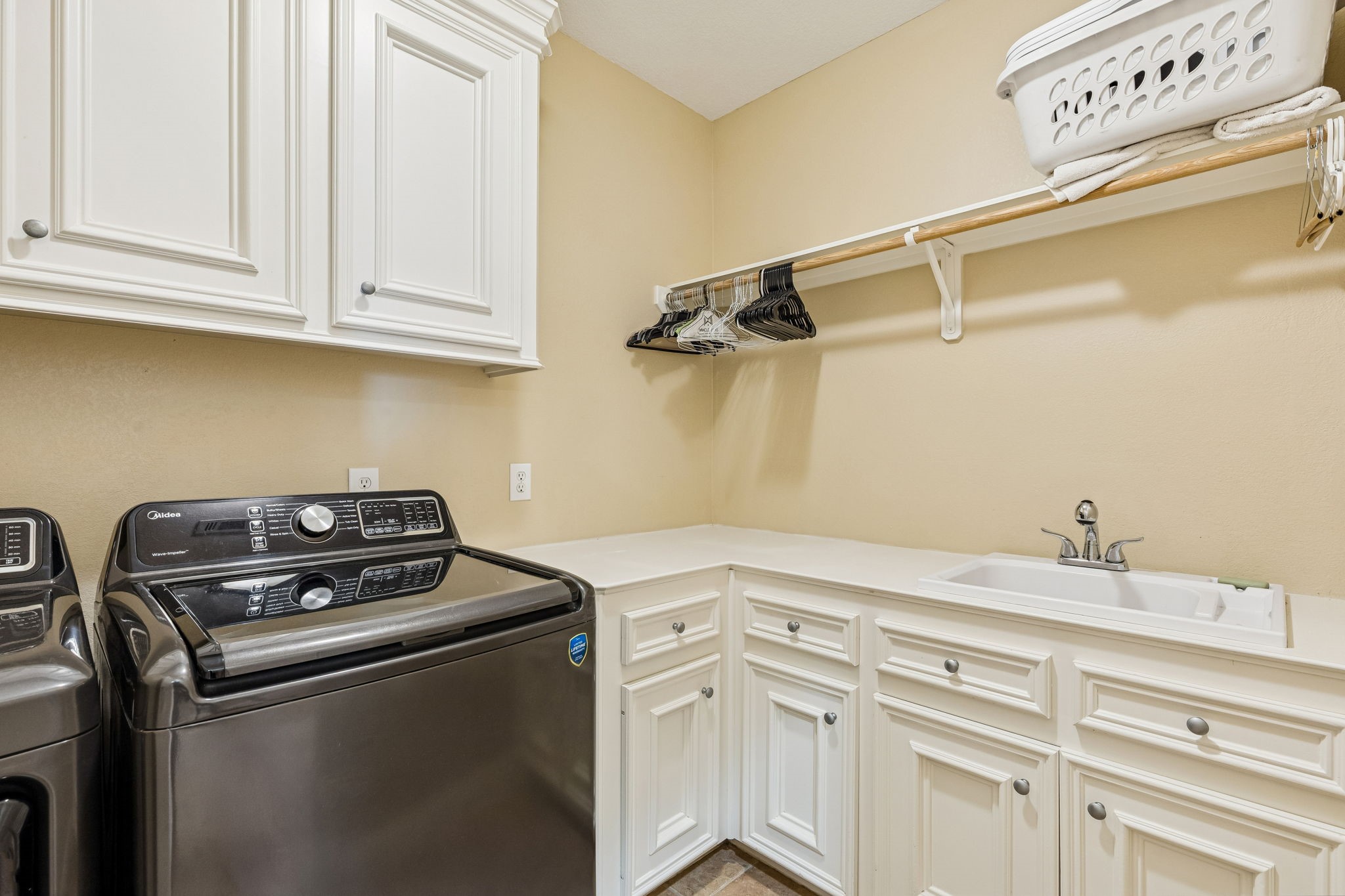 2217 Bernie Avenue Rosenberg, TX 77471 - Photo 19 of 25 The functional utility room features a built-in sink and extensive white cabinetry for organized storage. This space is equipped with both gas and electric dryer connections to suit any appliance preference.