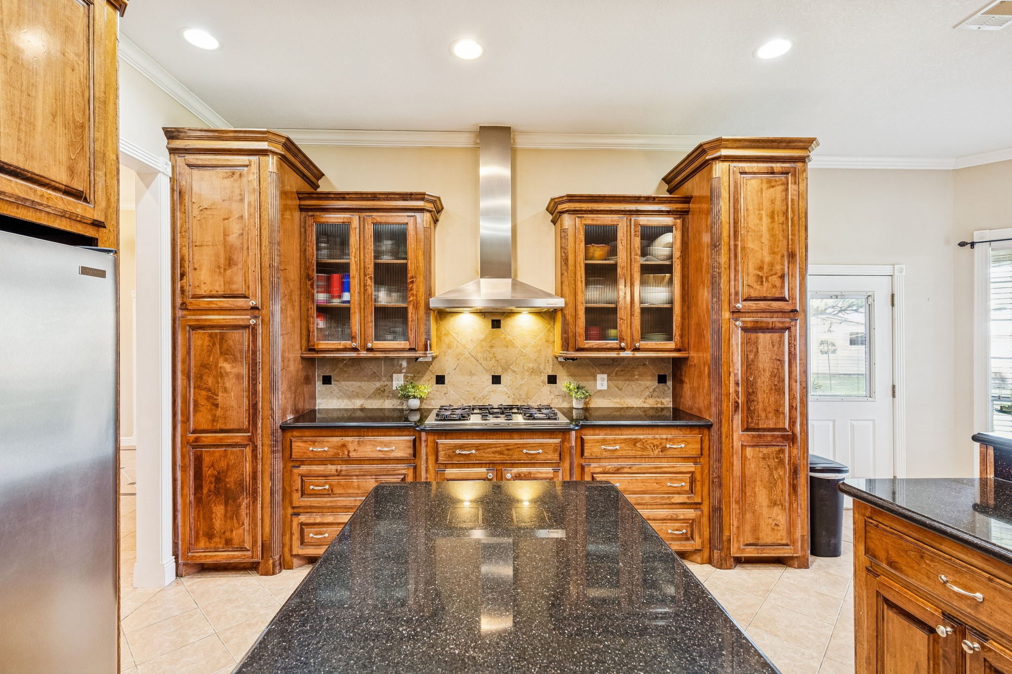 2217 Bernie Avenue Rosenberg, TX 77471 - Photo 7 of 25 The expansive kitchen is designed for efficiency with a central prep island and a professional-grade gas range. Modern pendant lighting and a decorative tile backsplash highlight the sophisticated finishes.