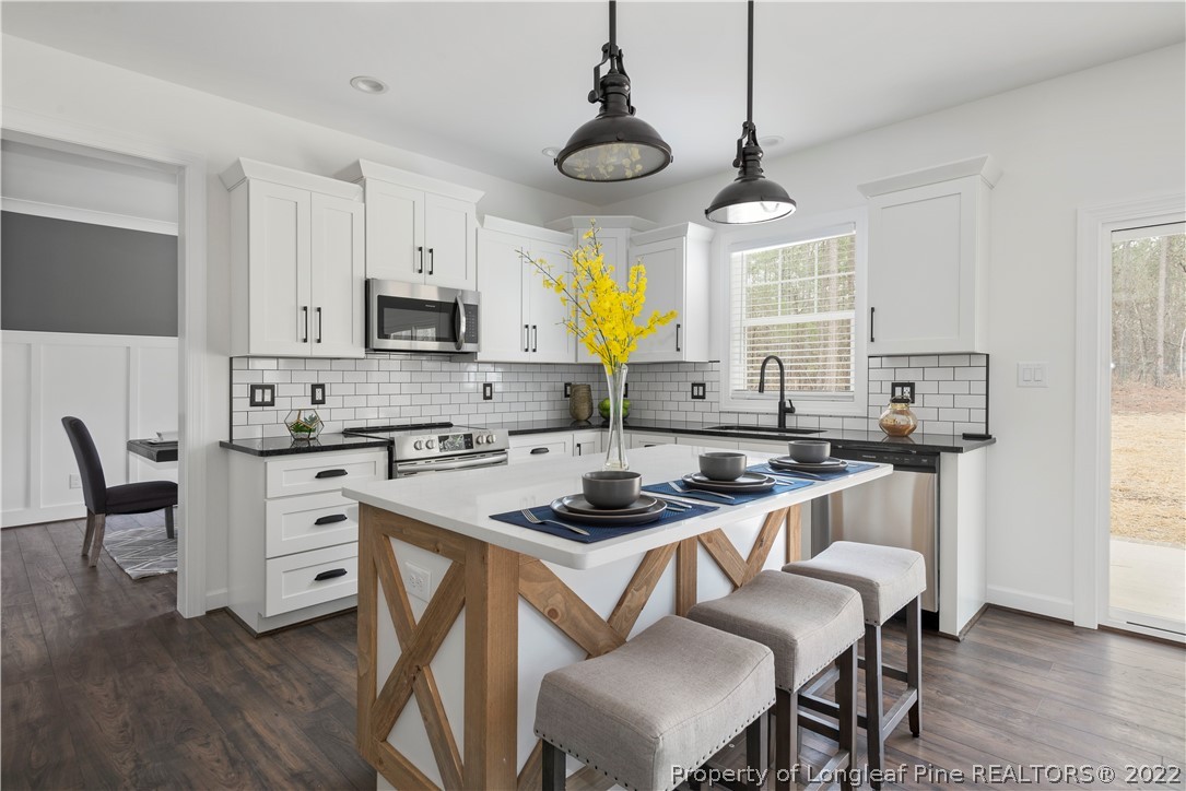 15581 Raccoon Run Road Wagram, NC 28396 - Photo 12 of 30 a kitchen with stainless steel appliances a stove a sink a stove a refrigerator cabinets and dining table