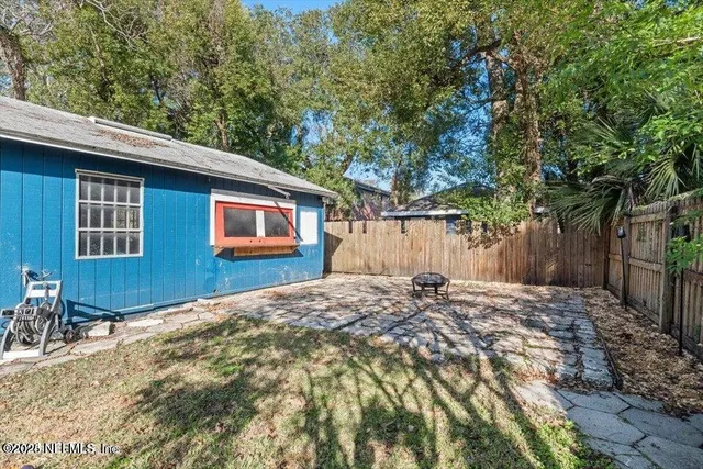 a backyard of a house with large trees and wooden fence