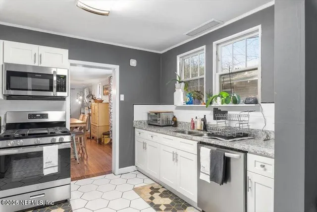 a kitchen with stainless steel appliances granite countertop a stove a sink and a microwave