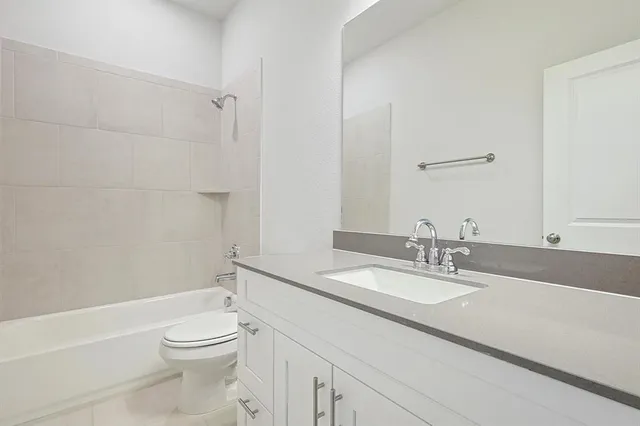 a bathroom with a granite countertop sink a toilet and shower