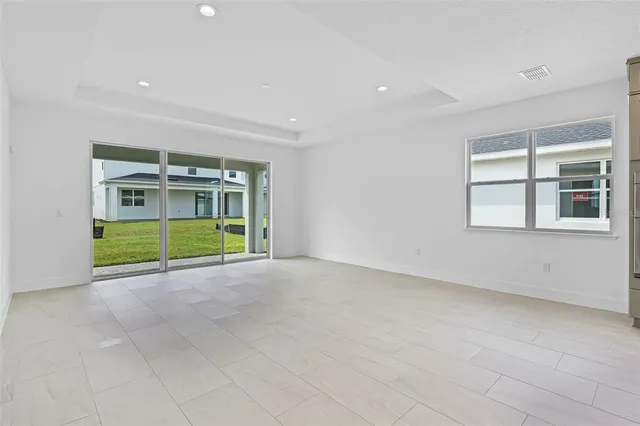 a view of an empty room with a window and kitchen view