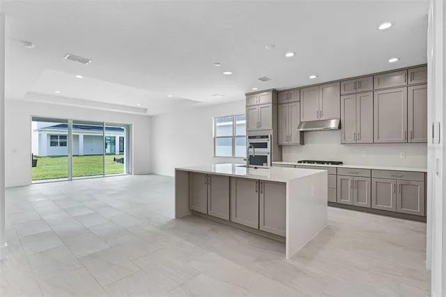 a large kitchen with kitchen island a sink a stove a counter space and cabinets