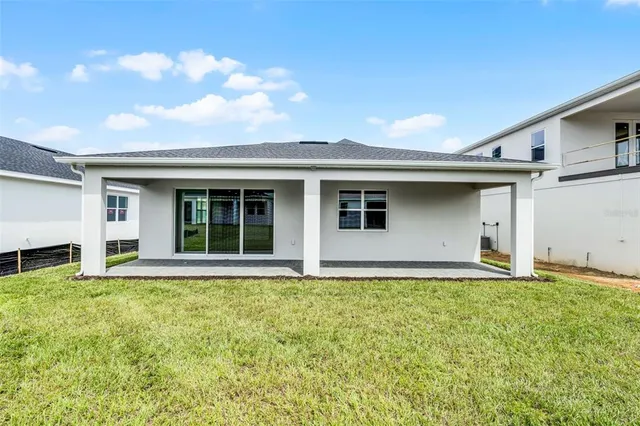 a front view of house with yard and trees in the background