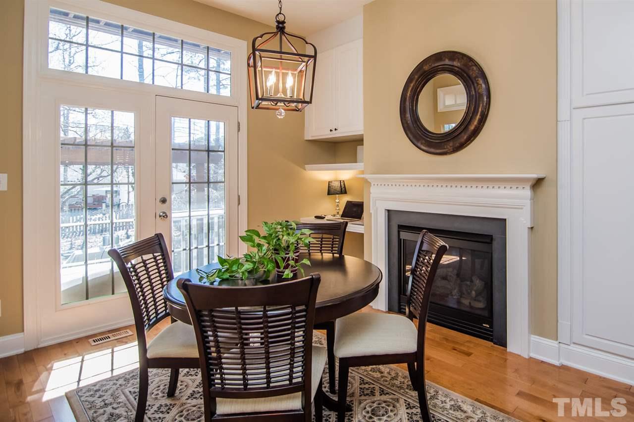 8214 Cushing Street Raleigh, NC 27613 - Photo 11 of 30 a dining room with furniture a fireplace and wooden floor