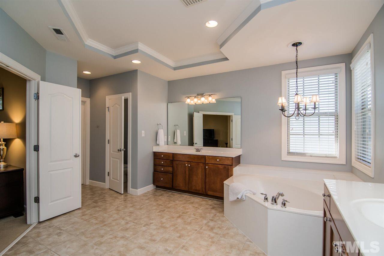 8214 Cushing Street Raleigh, NC 27613 - Photo 20 of 30 a large spacious bathroom with a tub sink and mirror