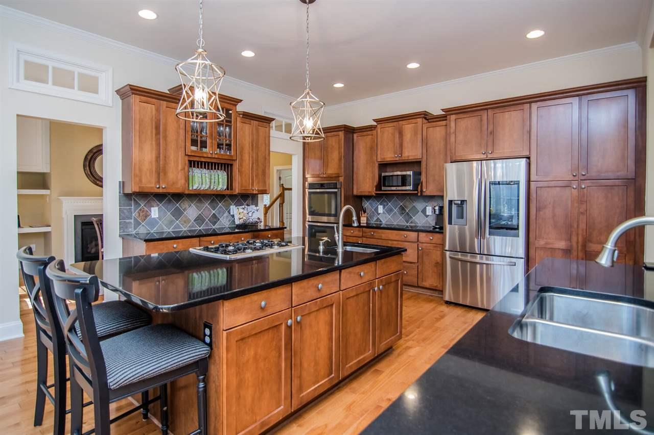 8214 Cushing Street Raleigh, NC 27613 - Photo 7 of 30 a kitchen with stainless steel appliances granite countertop a stove refrigerator a sink and a microwave