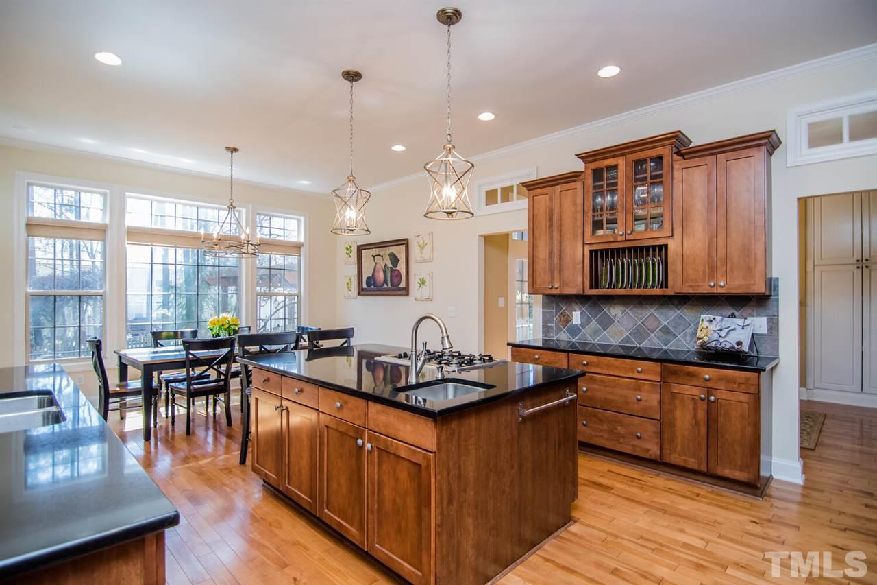 8214 Cushing Street Raleigh, NC 27613 - Photo 9 of 30 a kitchen with stainless steel appliances granite countertop a stove top oven a sink dishwasher a dining table and chairs with wooden floor