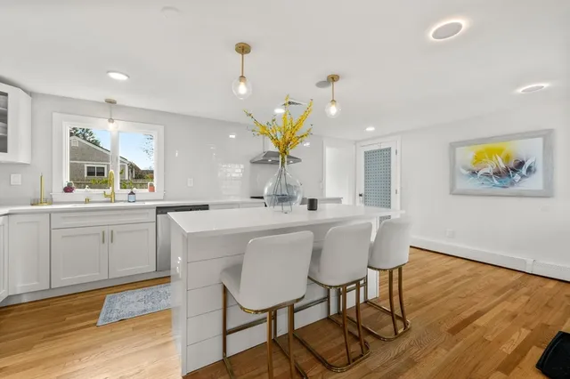 a kitchen with stainless steel appliances a dining table chairs stove and wooden floor