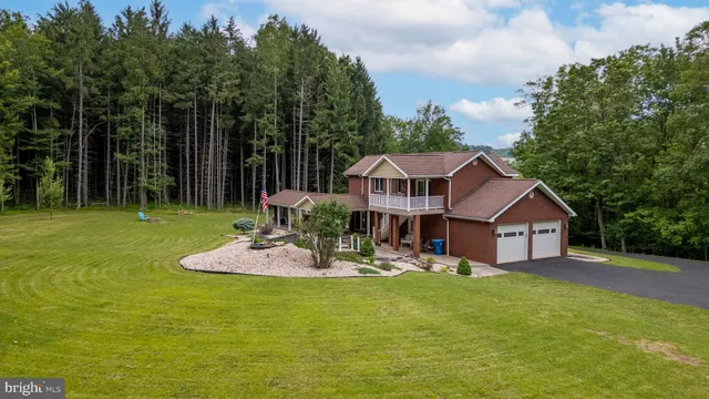 a backyard of a house with table and chairs plants and large tree