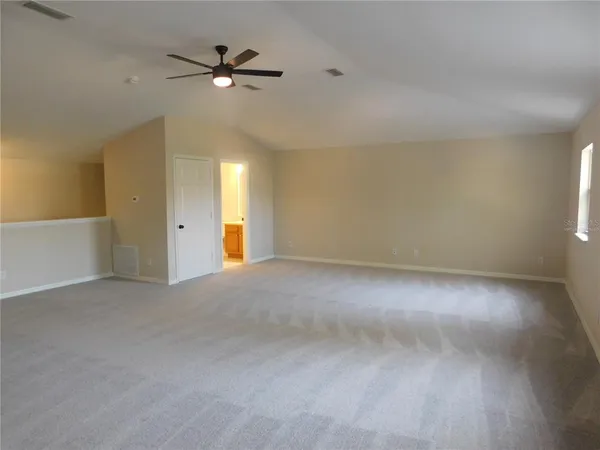 an empty room with chandelier fan and windows