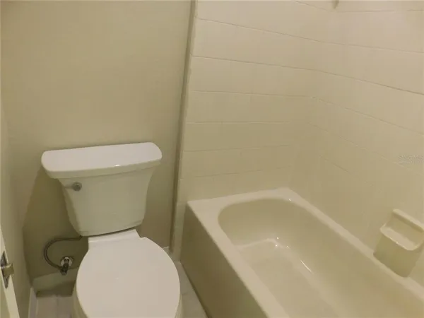 a white toilet sitting next to a white bath tub