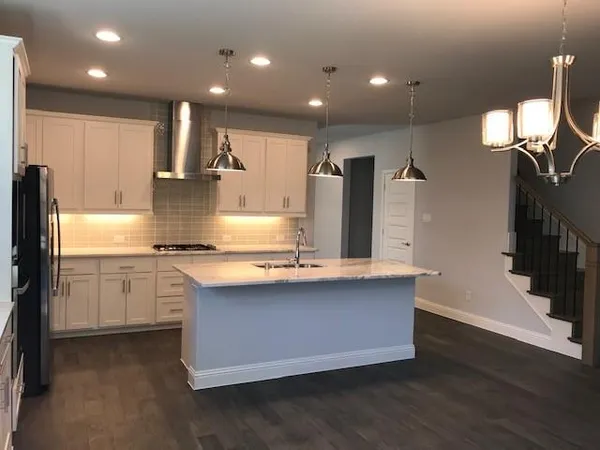 a kitchen with stainless steel appliances granite countertop a sink a refrigerator and a stove top oven