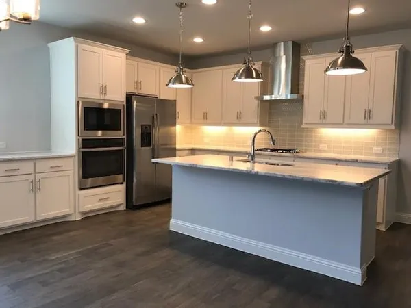a kitchen with kitchen island a counter space a sink appliances and cabinets
