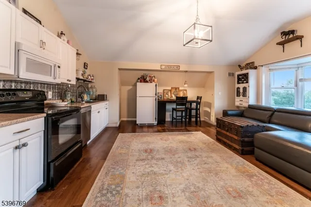 a view of a kitchen with stainless steel appliances granite countertop a stove top oven a sink dishwasher and white cabinets