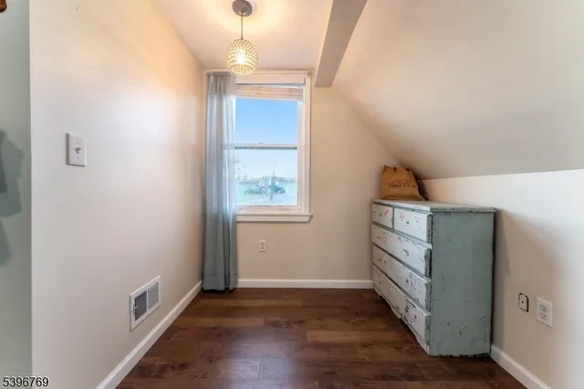 an empty room with wooden floor cabinet and windows