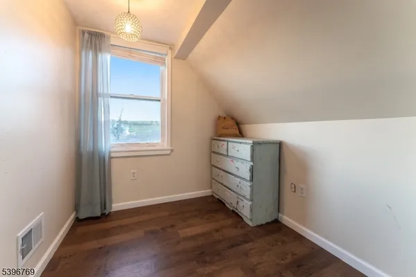 an empty room with wooden floor cabinet and windows