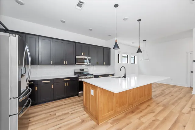 a kitchen with kitchen island stainless steel appliances a sink a stove a refrigerator center island and cabinets