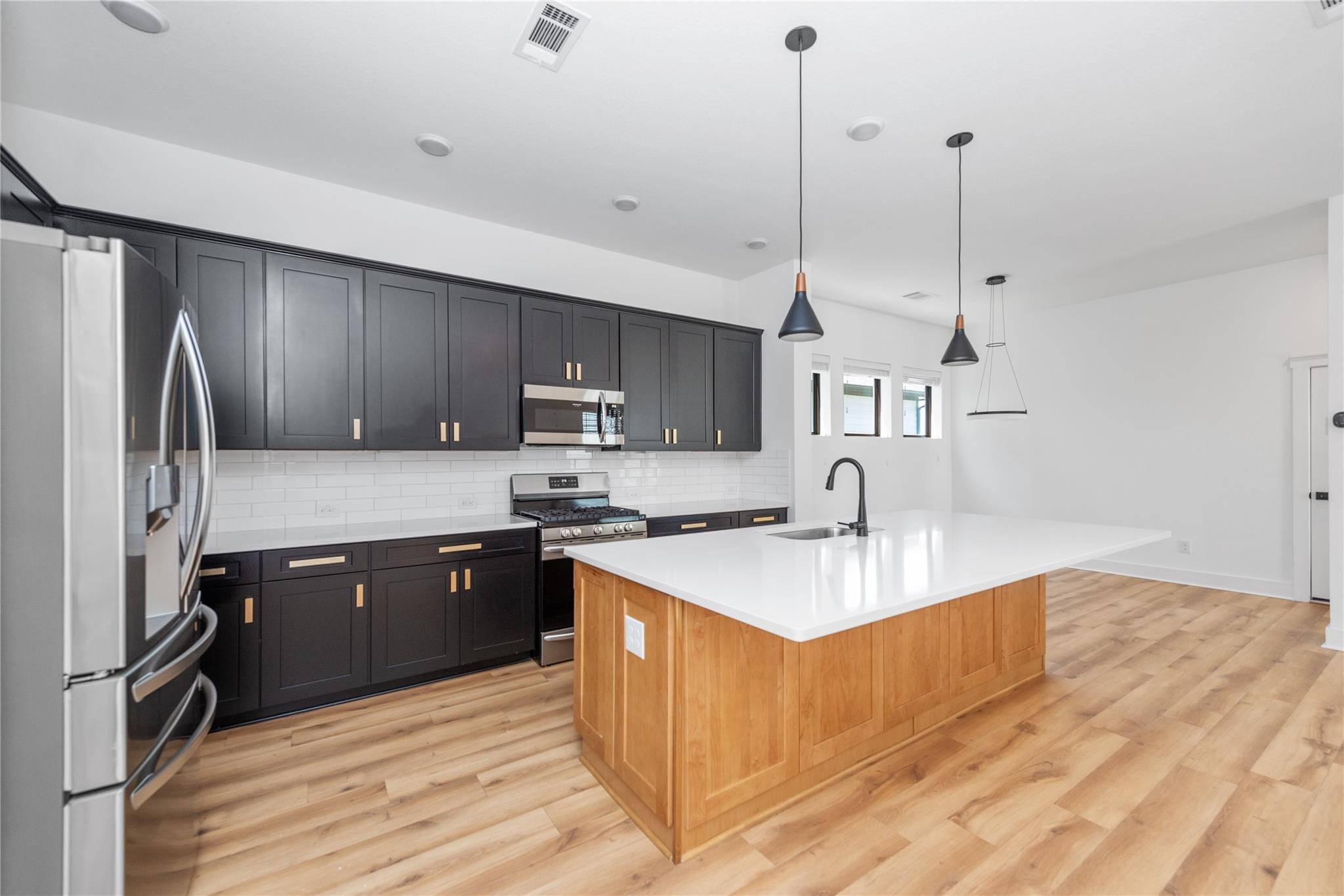 18618 Courteous Way Cypress, TX 77433 - Photo 13 of 30 a kitchen with kitchen island stainless steel appliances a sink a stove a refrigerator center island and cabinets
