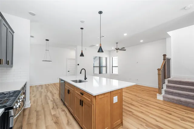 a kitchen with stainless steel appliances granite countertop a sink stove and wooden floor