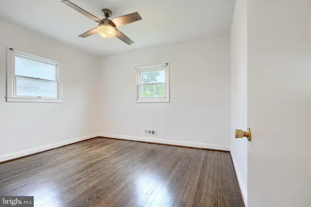 an empty room with wooden floor and ceiling fan