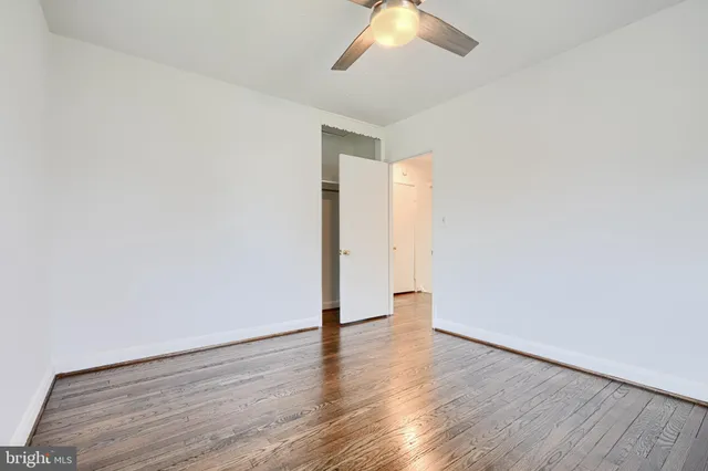 an empty room with wooden floor and ceiling fan