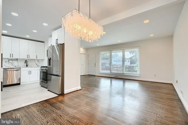 a kitchen with stainless steel appliances granite countertop a refrigerator a sink dishwasher a stove and white countertops with wooden floor