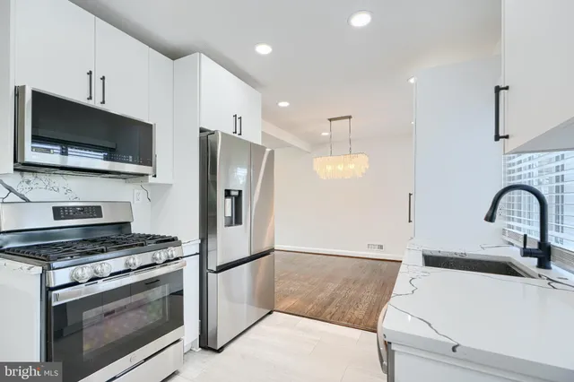 a kitchen with stainless steel appliances white cabinets a sink and a stove