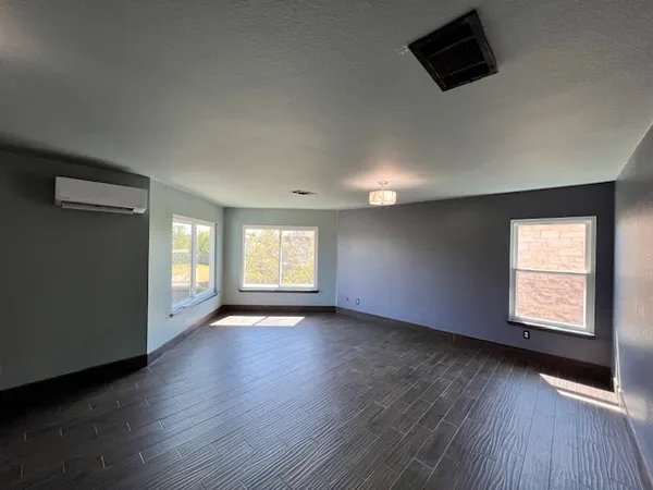 an empty room with wooden floor and windows