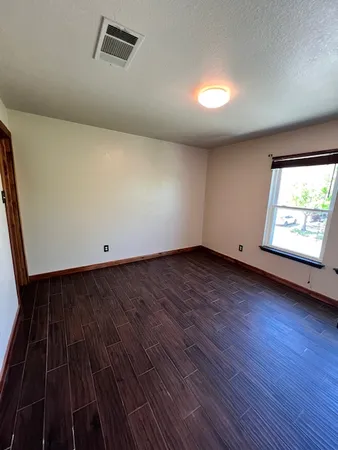 an empty room with wooden floor and windows