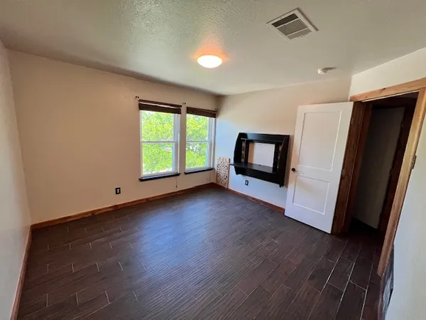 an empty room with wooden floor and windows