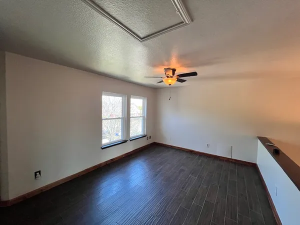 an empty room with wooden floor and windows