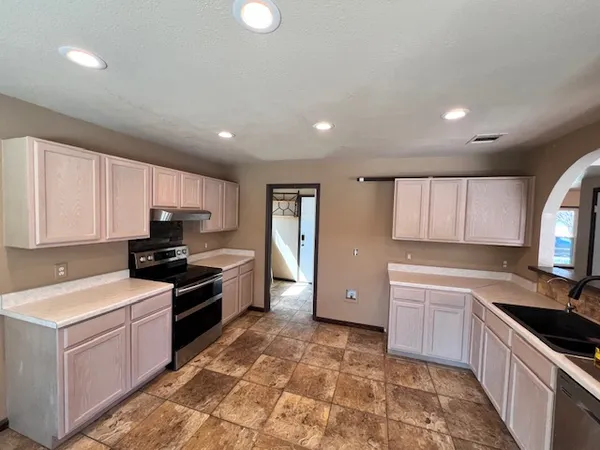 a kitchen with granite countertop a sink a stove and refrigerator