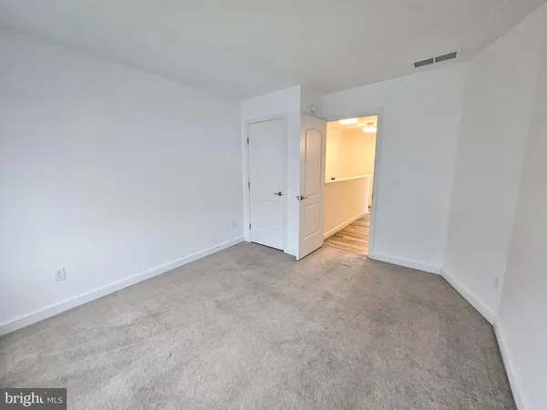 a view of a hallway with wooden floor and a bathroom