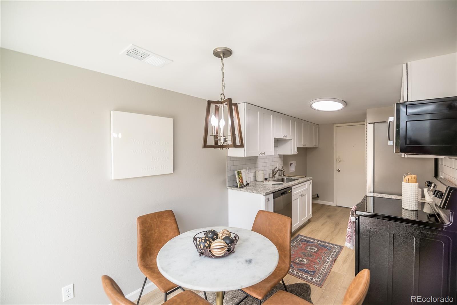 7906 Chase Circle, Unit 143 Arvada, CO 80003 - Photo 7 of 38 a kitchen with stainless steel appliances granite countertop a sink dishwasher a stove a refrigerator with a dining table and chairs