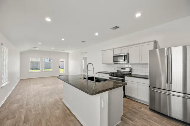 a kitchen with stainless steel appliances granite countertop a sink stove and refrigerator