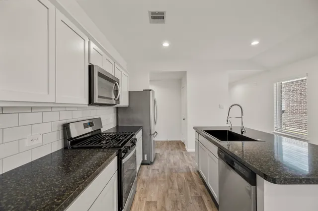 a kitchen with granite countertop a sink stainless steel appliances and cabinets