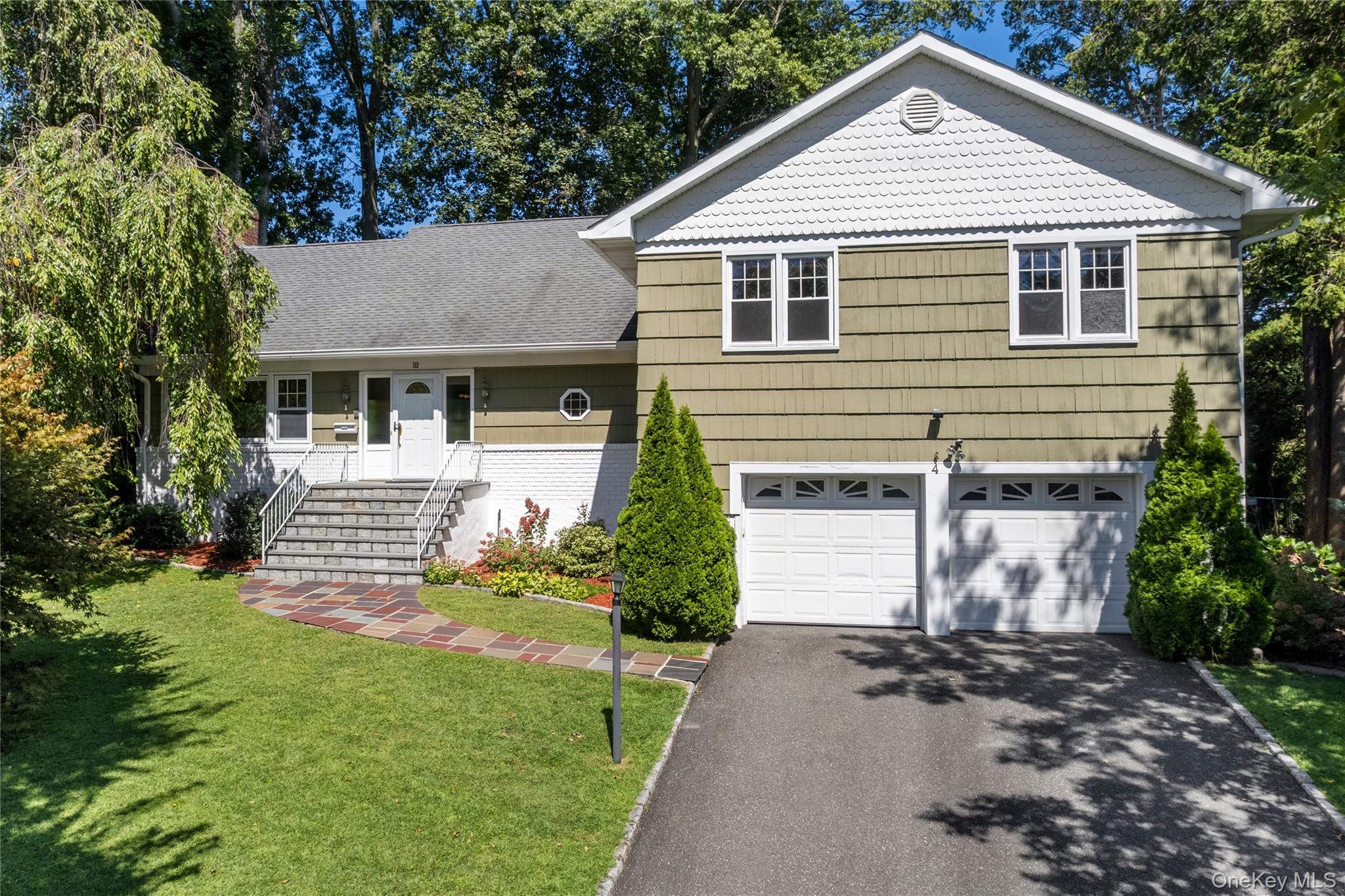Tri-level home featuring asphalt driveway, a front lawn, and an attached garage