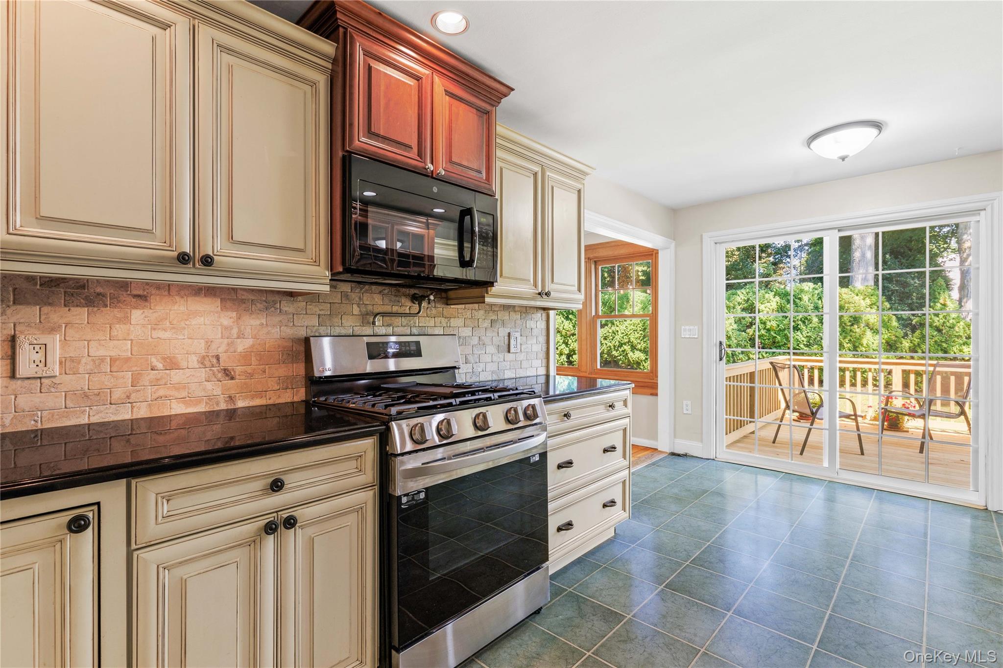 4 Mark Drive Rye Brook, NY 10573 - Photo 14 of 47 Kitchen with cream cabinets, stainless steel gas stove, black microwave, backsplash, and dark tile patterned floors