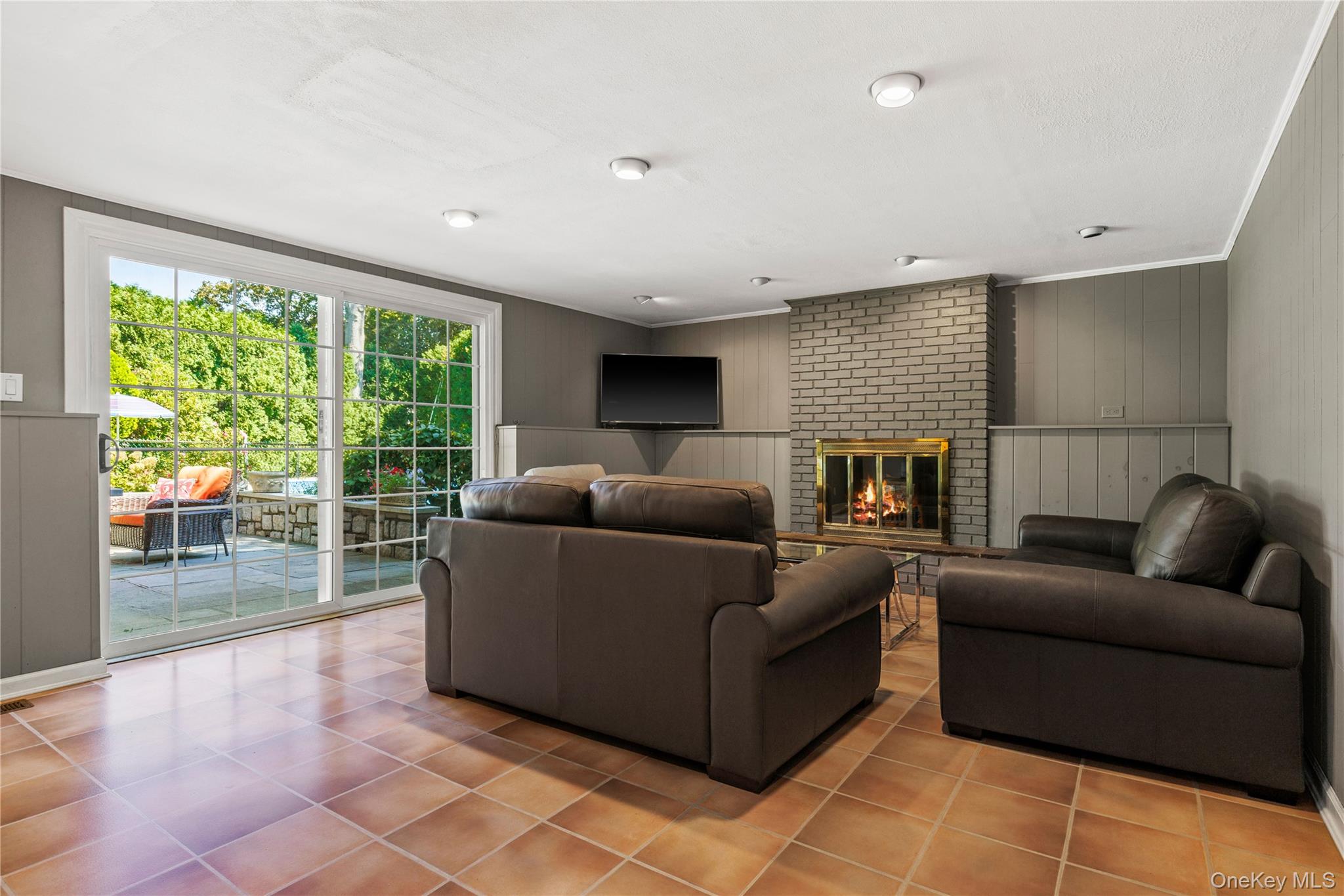 4 Mark Drive Rye Brook, NY 10573 - Photo 25 of 47 Tiled living area featuring wood walls, a fireplace, crown molding, and a decorative wall