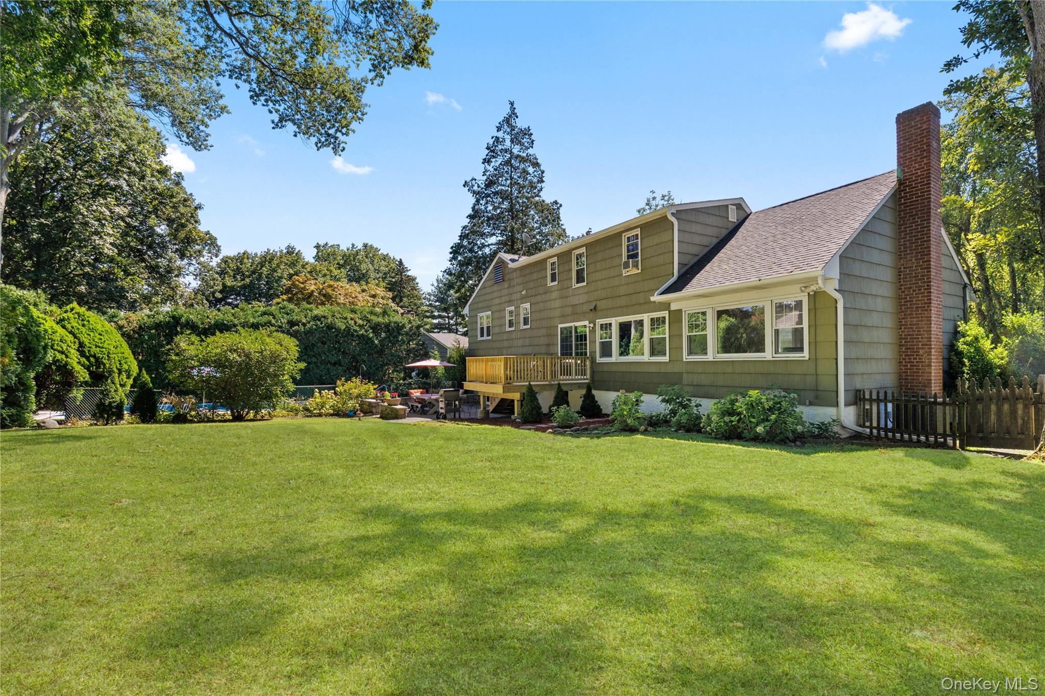 4 Mark Drive Rye Brook, NY 10573 - Photo 35 of 47 Back of house featuring a wooden deck, a chimney, roof with shingles, and view of wooded area