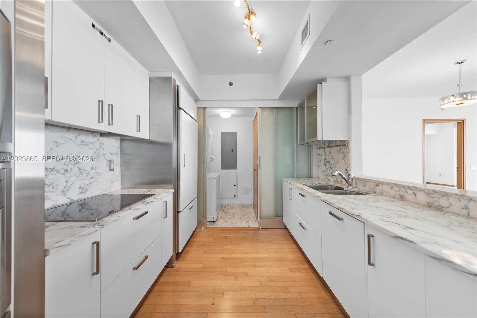 450 Alton Road, Unit 3206 Miami Beach, FL 33139 - Photo 6 of 25 a large white kitchen with granite countertop a sink and dishwasher stove a refrigerator a sink with wooden floors